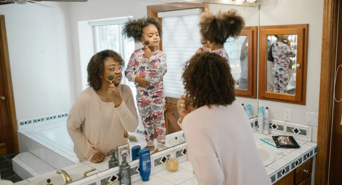 A mother and daughter enjoy a morning skincare ritual together in the bathroom.