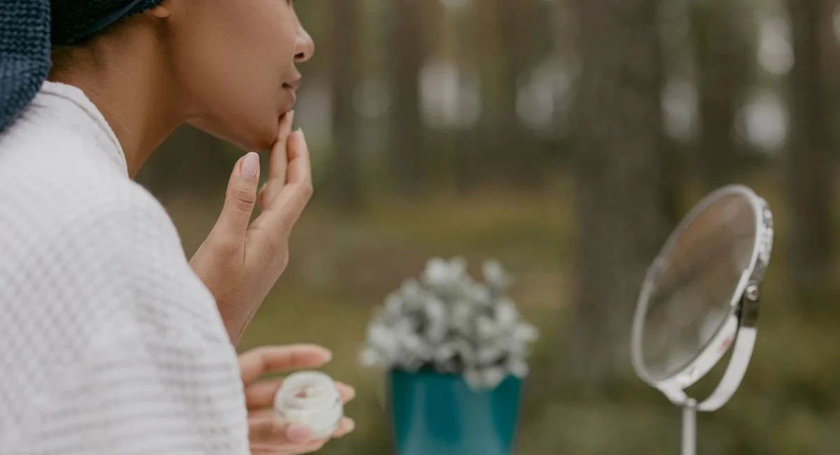 Woman enjoying skincare routine in serene forest setting. Self-care, beauty, and relaxation outdoors.