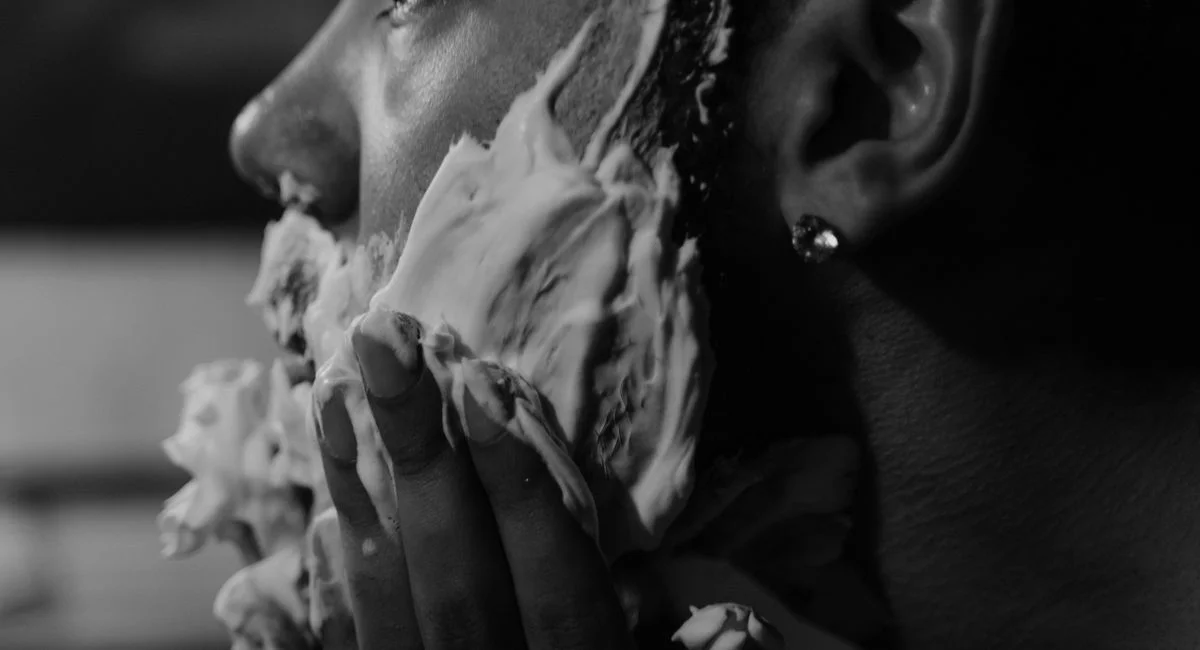 Black and white photo of a man applying shaving cream with a focused expression.