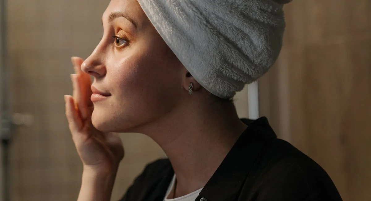 A woman applying skincare for a radiant skin routine.