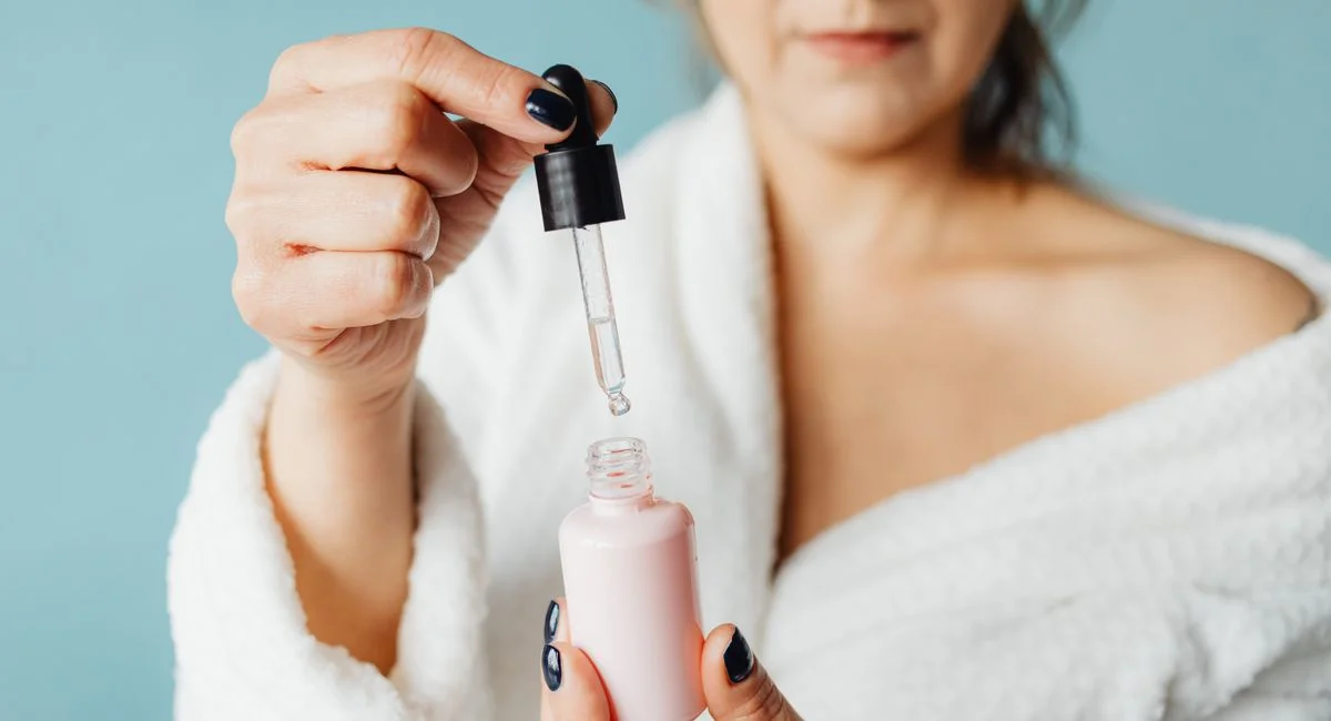 Close-up of an adult woman applying serum with a pipette indoors.